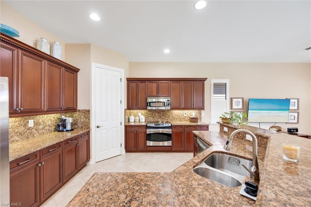 7660 Cottesmore Drive Naples, FL 34113 - Photo 11 of 50 a kitchen with stainless steel appliances granite countertop a sink stove and refrigerator