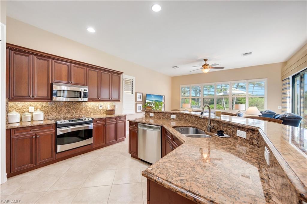 7660 Cottesmore Drive Naples, FL 34113 - Photo 12 of 50 a kitchen with stainless steel appliances granite countertop a stove top oven a sink a counter space and cabinets