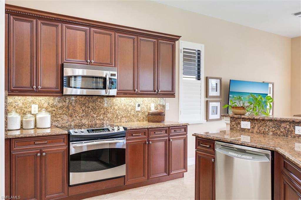 7660 Cottesmore Drive Naples, FL 34113 - Photo 14 of 50 a kitchen with granite countertop wooden cabinets and a stove top oven