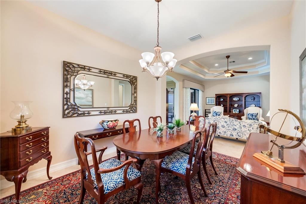 7660 Cottesmore Drive Naples, FL 34113 - Photo 15 of 50 a dining room with wooden floor a chandelier a wooden table and chairs