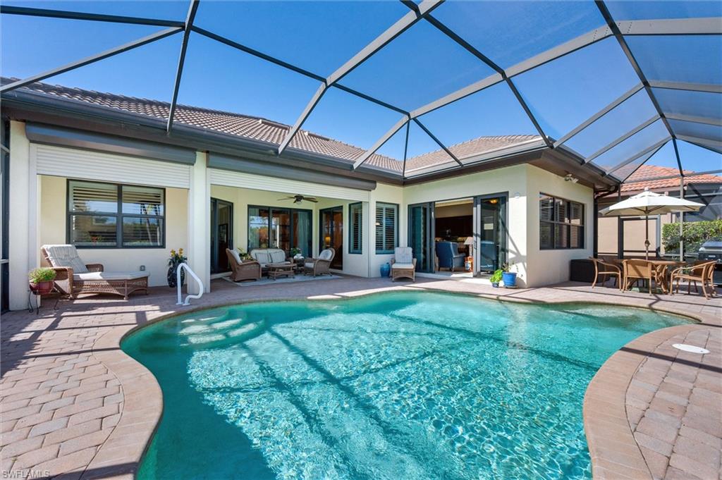 7660 Cottesmore Drive Naples, FL 34113 - Photo 25 of 50 a view of a patio with table and chairs under an umbrella