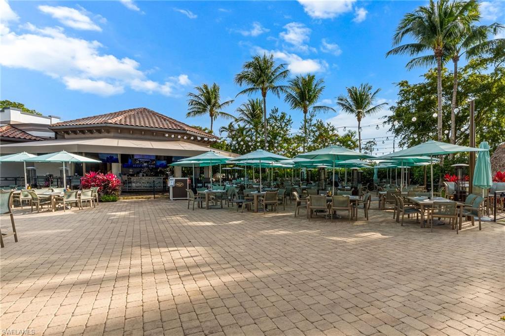 7660 Cottesmore Drive Naples, FL 34113 - Photo 47 of 50 a view of the patio with dining table and chairs under an umbrella