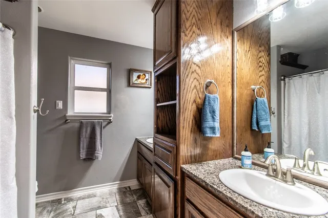 a bathroom with a granite countertop sink a mirror and a shower