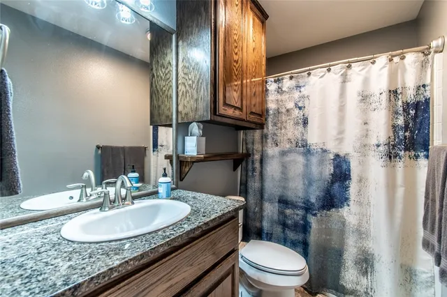 a bathroom with a granite countertop sink toilet a mirror and shower