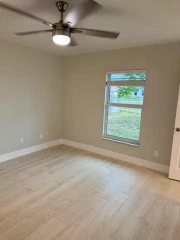 an empty room with a window and ceiling fan