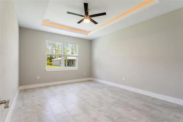 an empty room with windows and ceiling fan