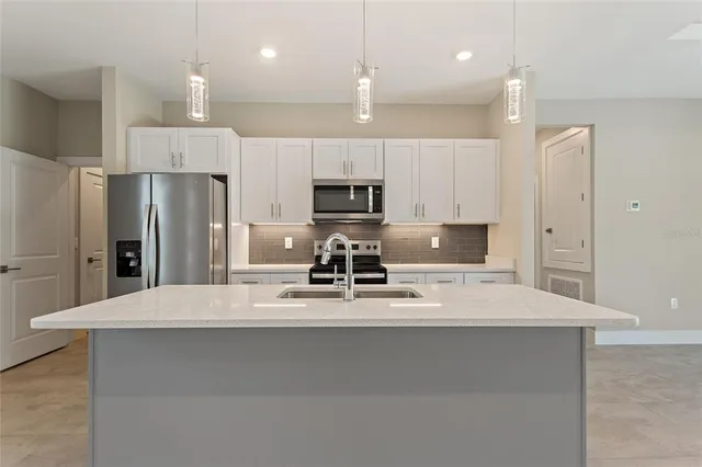 a large kitchen with a large counter top stainless steel appliances and cabinets