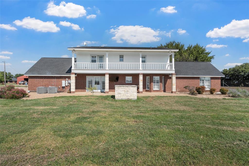 5112 Old Caufield Ranch Road McGregor, TX 76657 - Photo 32 of 38 Rear view of house with a lawn, brick siding, a balcony, and a patio area
