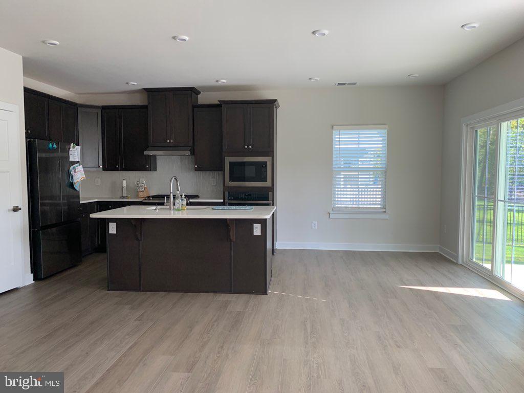 37354 Kestrel Way Ocean View, DE 19970 - Photo 3 of 18 a kitchen with kitchen island granite countertop a sink cabinets and stainless steel appliances