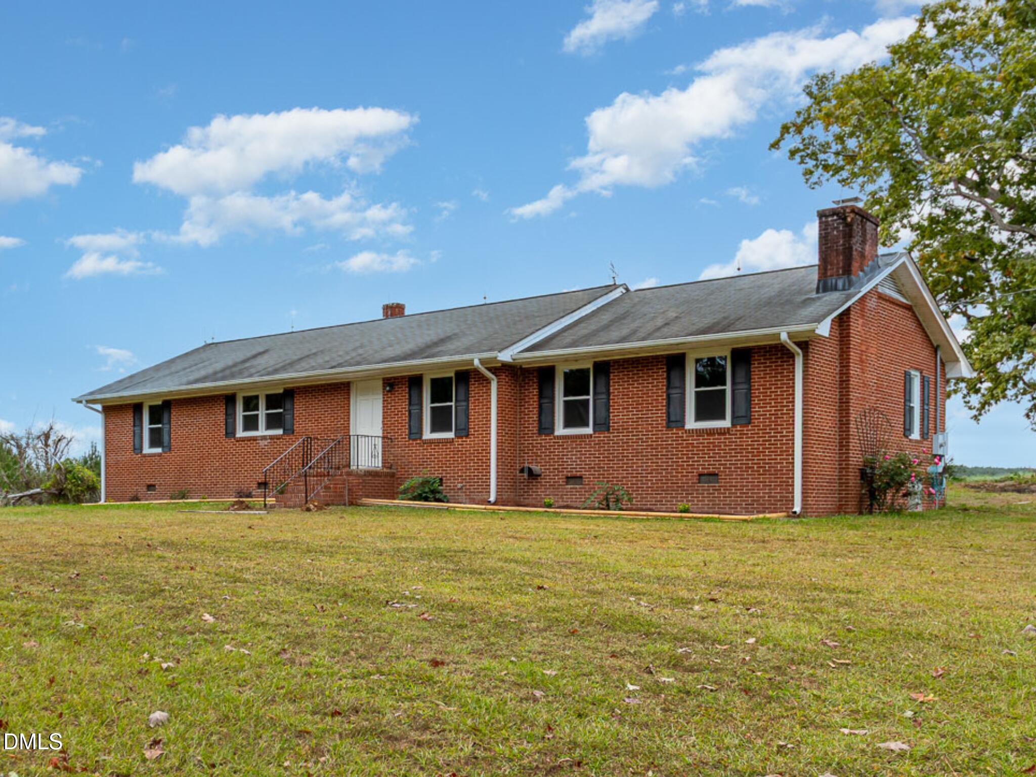 a front view of house with yard and trees in the background