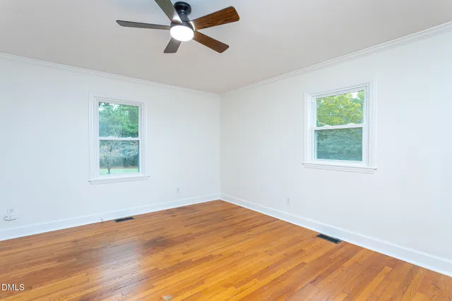 a view of a big room with wooden floor and windows