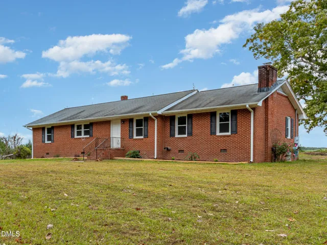 a front view of house with yard and trees in the background