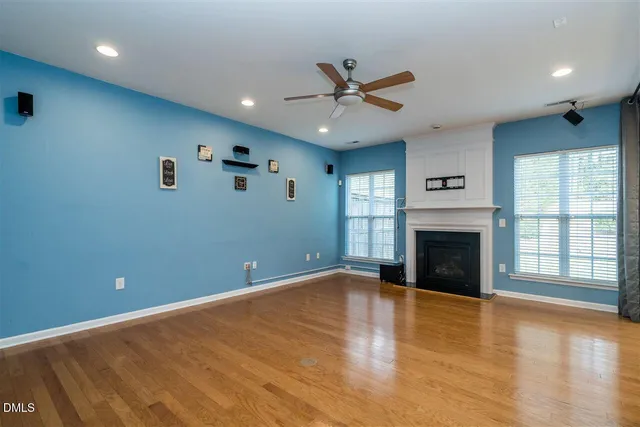 an empty room with windows fireplace and wooden floor