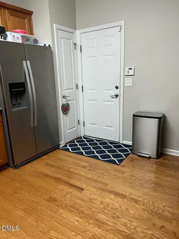 a view of a refrigerator in kitchen and an empty room