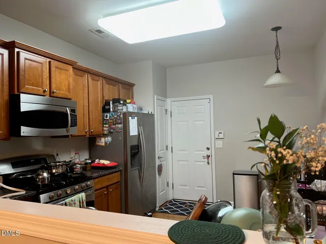 a kitchen with stainless steel appliances a refrigerator a stove a sink and a potted plant