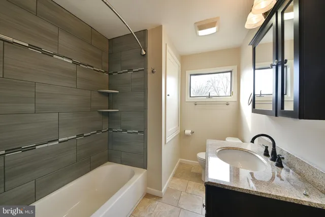 a bathroom with a granite countertop sink a mirror and a bathtub