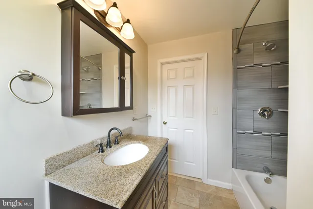 a bathroom with a granite countertop sink a mirror and shower