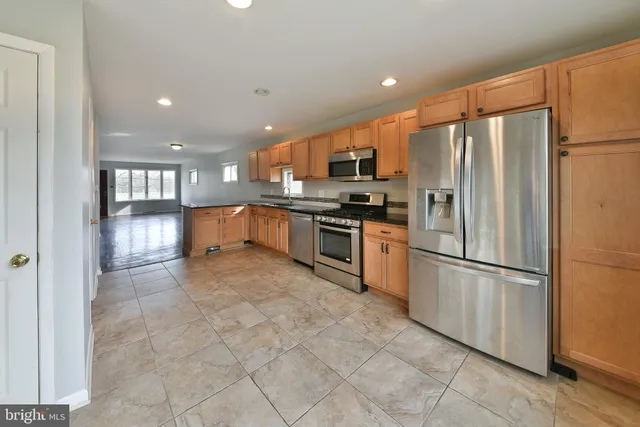 a kitchen with stainless steel appliances granite countertop a refrigerator a stove a sink a microwave and a refrigerator