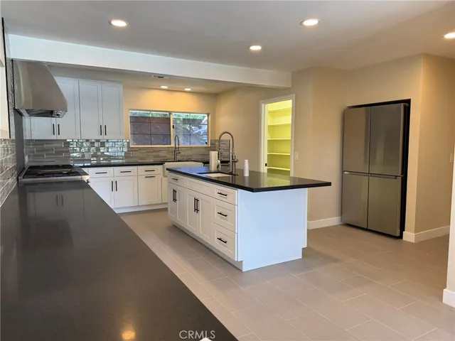 a kitchen with granite countertop a sink stove refrigerator and cabinets