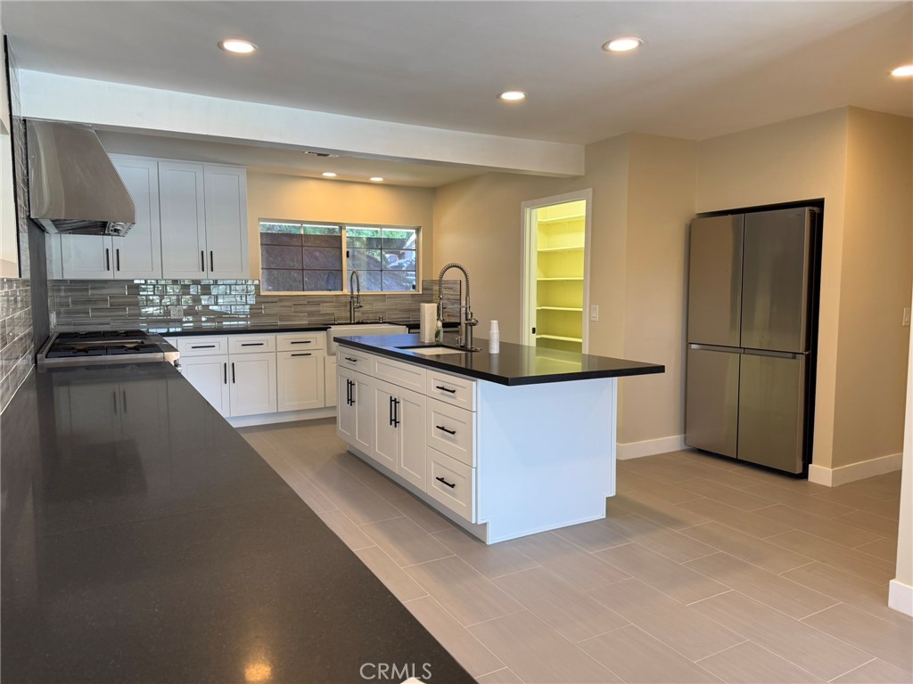 a kitchen with granite countertop a sink stove refrigerator and cabinets