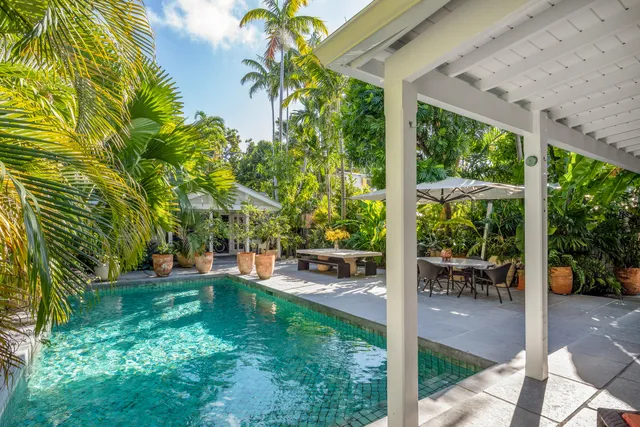 a backyard of a house with table and chairs under an umbrella
