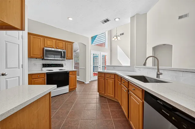 a large kitchen with granite countertop a sink and white cabinets
