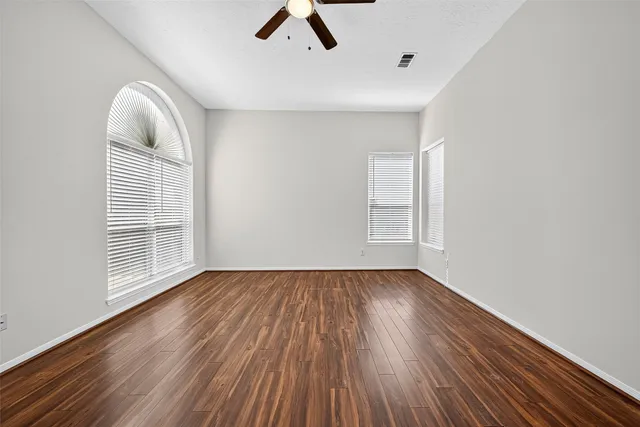 a view of empty room with wooden floor and fan