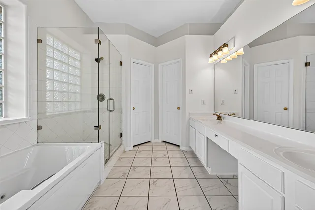 a spacious bathroom with a granite countertop sink a mirror and a bathtub with shower