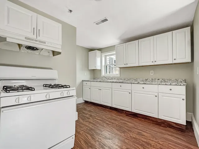 a kitchen with granite countertop white cabinets and white appliances