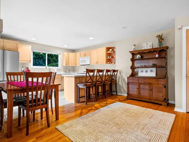 a open kitchen with stainless steel appliances granite countertop a stove top oven a dining table and chairs with wooden floor