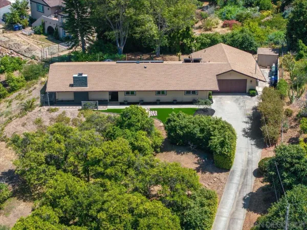 an aerial view of a house with a yard and large tree