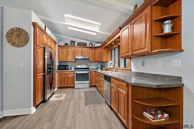 a kitchen with stainless steel appliances granite countertop a refrigerator a stove and a sink