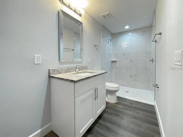 a bathroom with a granite countertop sink a toilet and shower