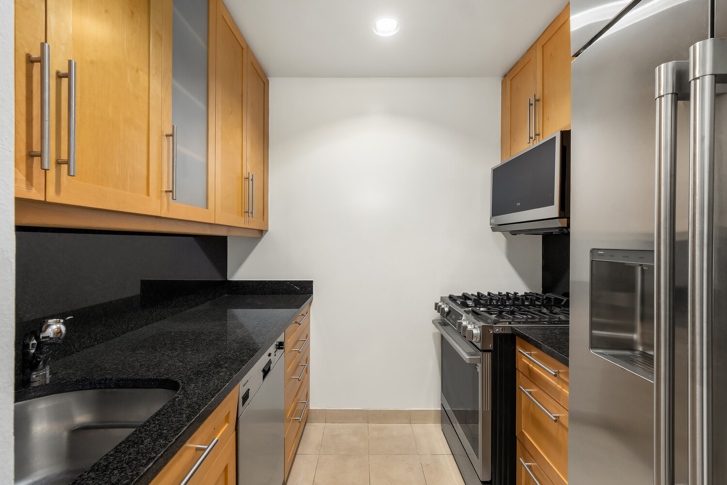 100 United Nations Plaza, Unit 35E Manhattan, NY 10017 - Photo 3 of 11 a kitchen with stainless steel appliances granite countertop a stove and a refrigerator