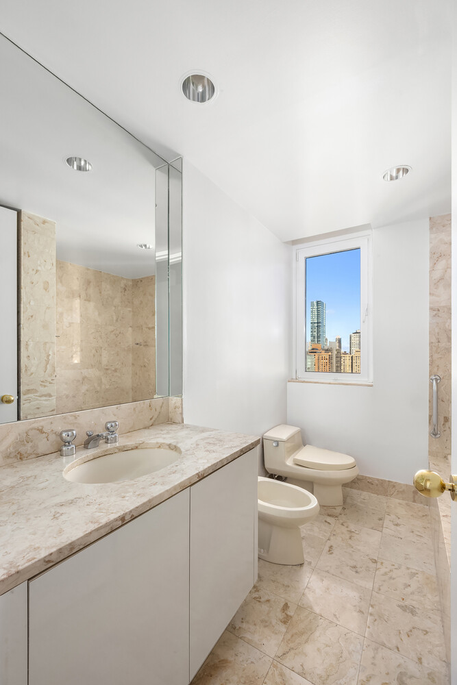 100 United Nations Plaza, Unit 35E Manhattan, NY 10017 - Photo 7 of 11 a bathroom with a granite countertop sink a toilet and a mirror