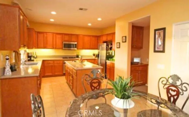 a kitchen with stainless steel appliances a dining table chairs in it and a window