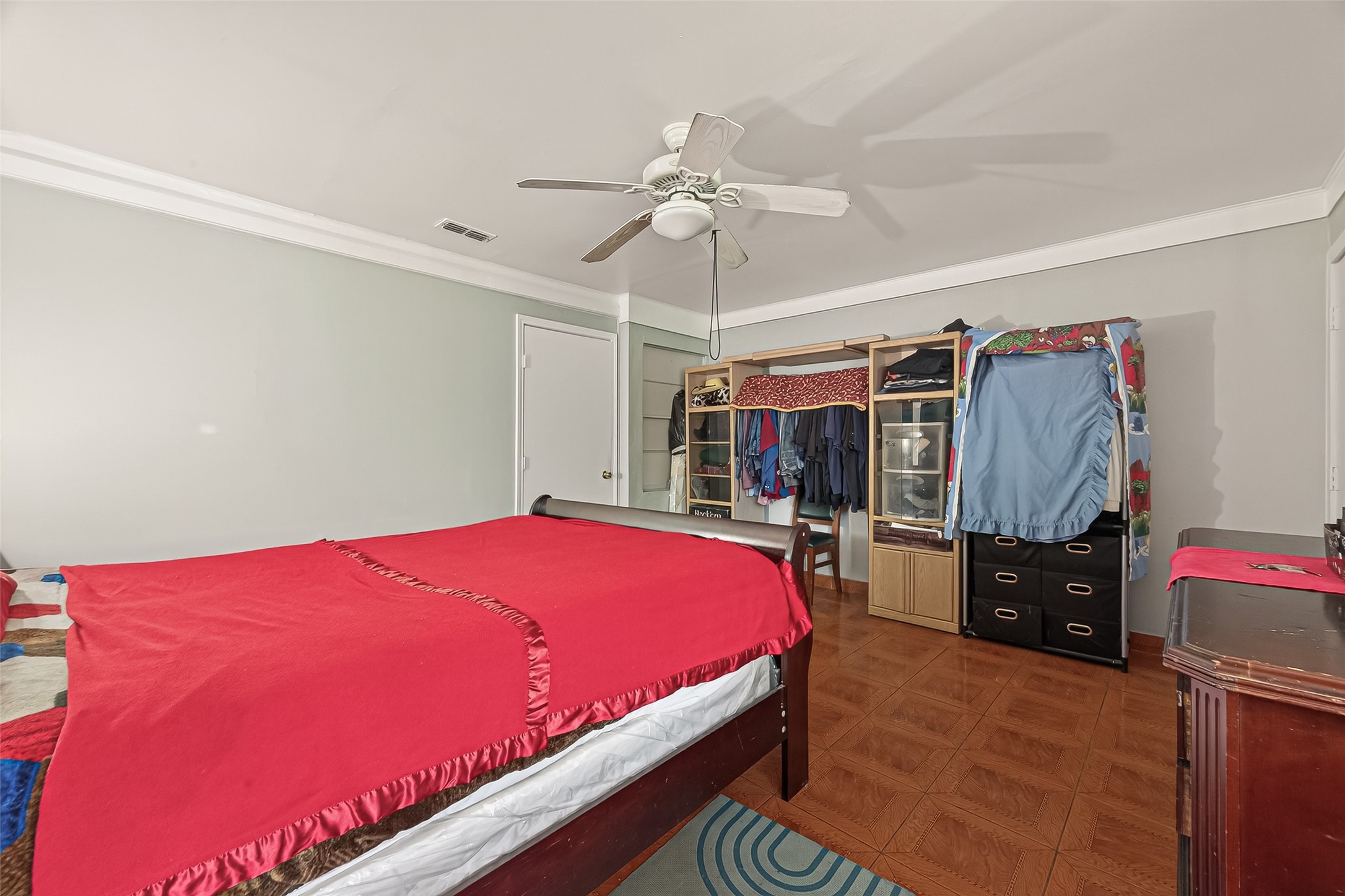 9030 Troulon Drive Houston, TX 77036 - Photo 13 of 34 Spacious bedroom offering tile flooring, a ceiling fan, and ample space for furnishings, including open shelving for storage.
