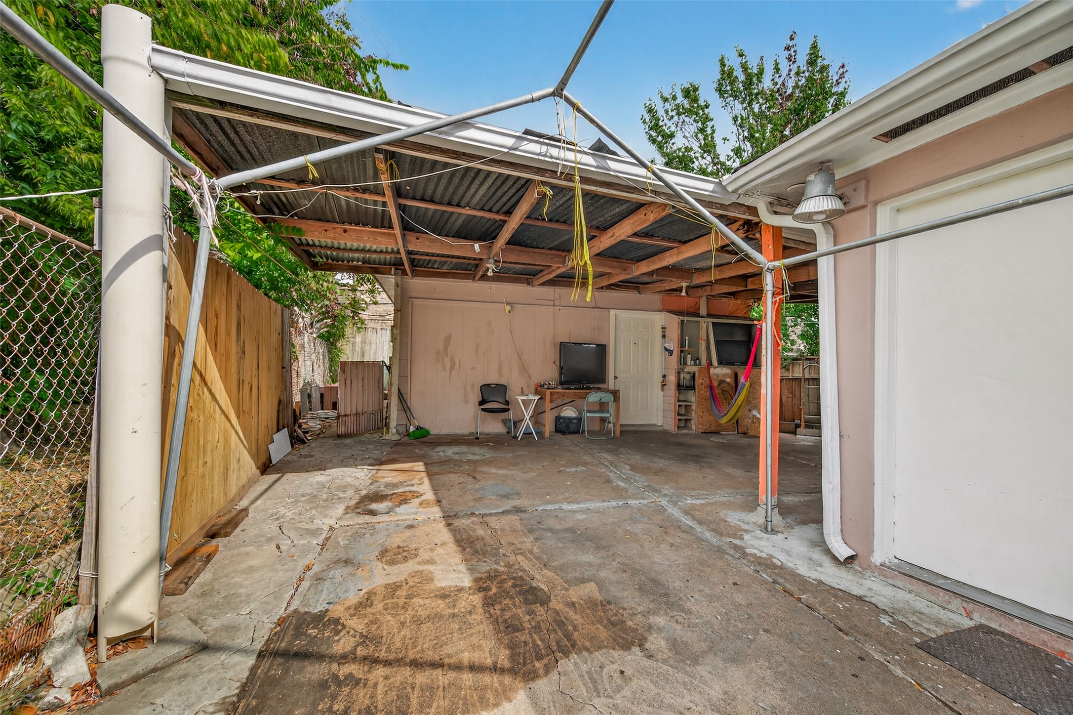 9030 Troulon Drive Houston, TX 77036 - Photo 27 of 34 Spacious covered carport or patio area with a durable concrete floor and secure fencing, offering sheltered outdoor utility space.