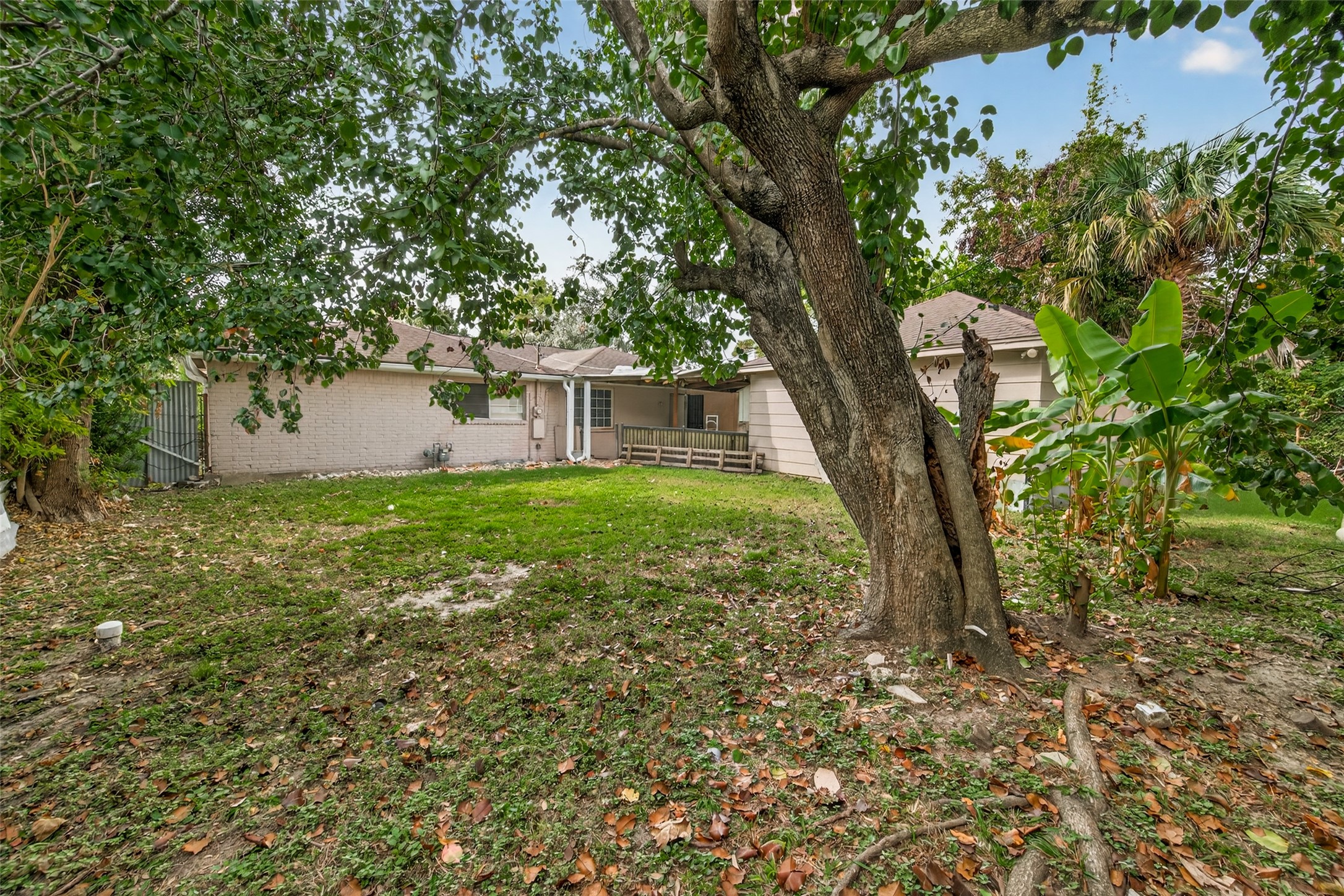 9030 Troulon Drive Houston, TX 77036 - Photo 31 of 34 Expansive backyard featuring a lush lawn, established trees, and charming deck connecting the main house to a separate structure.