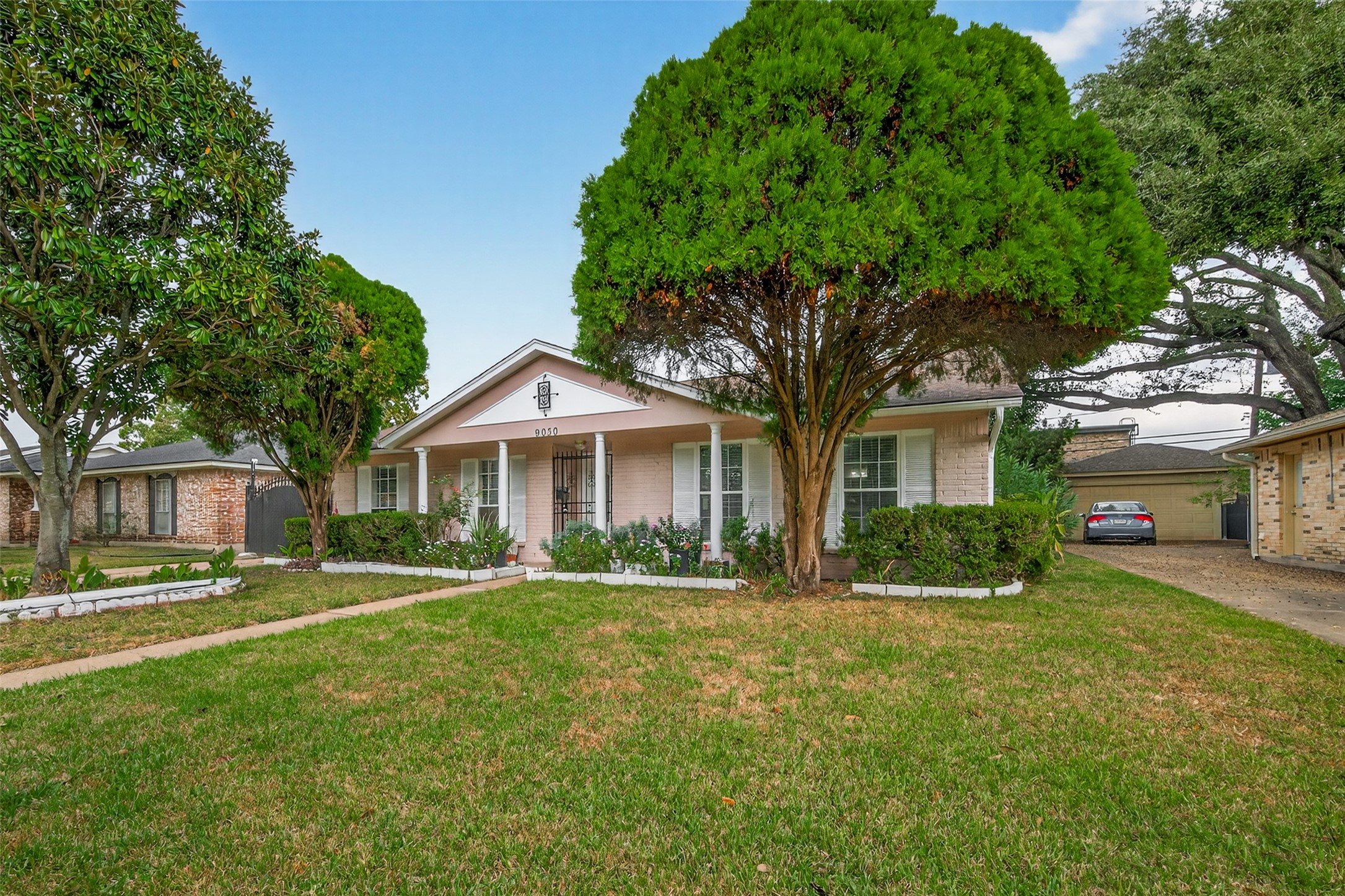 9030 Troulon Drive Houston, TX 77036 - Photo 33 of 34 Expansive front view highlighting the property's generous lawn, prominent shade trees, and a visible two-car garage at the rear.