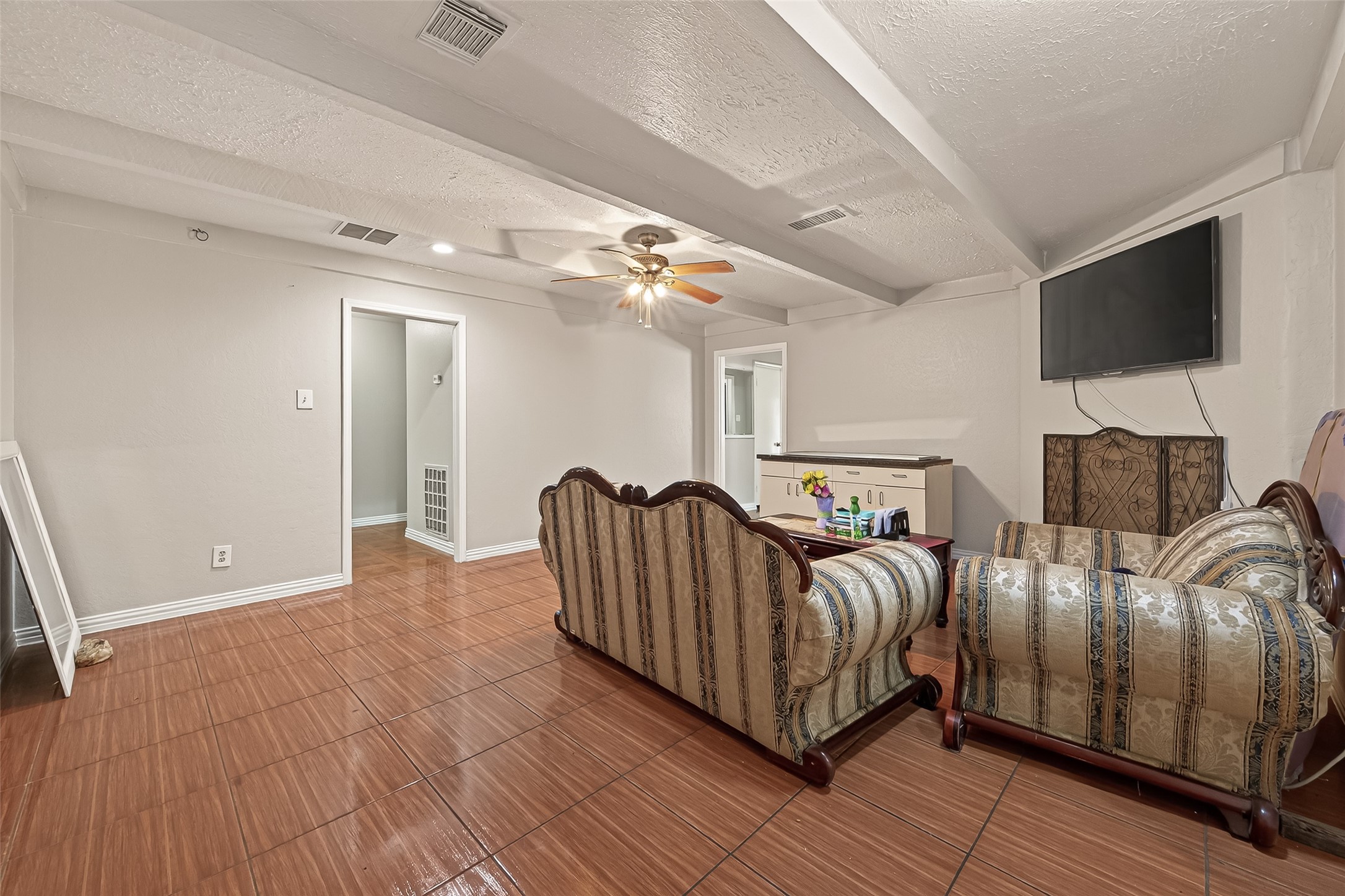 9030 Troulon Drive Houston, TX 77036 - Photo 4 of 34 Spacious living room boasting durable tile flooring, a refreshing ceiling fan, and ample space for comfortable seating and entertainment.