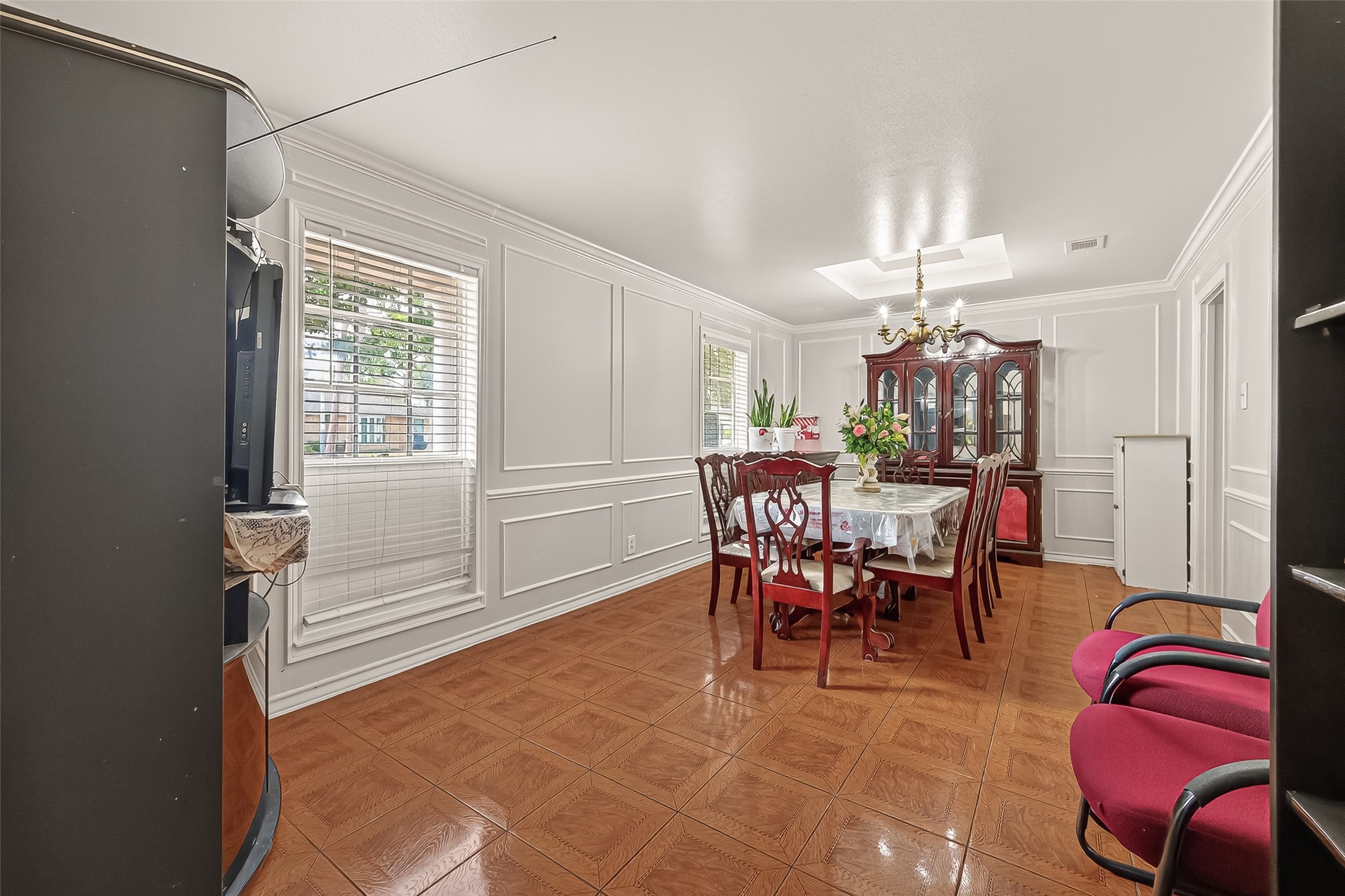 9030 Troulon Drive Houston, TX 77036 - Photo 7 of 34 Elegant dining room featuring detailed wainscoting, a classic chandelier, and warm tile flooring, ideal for formal gatherings.