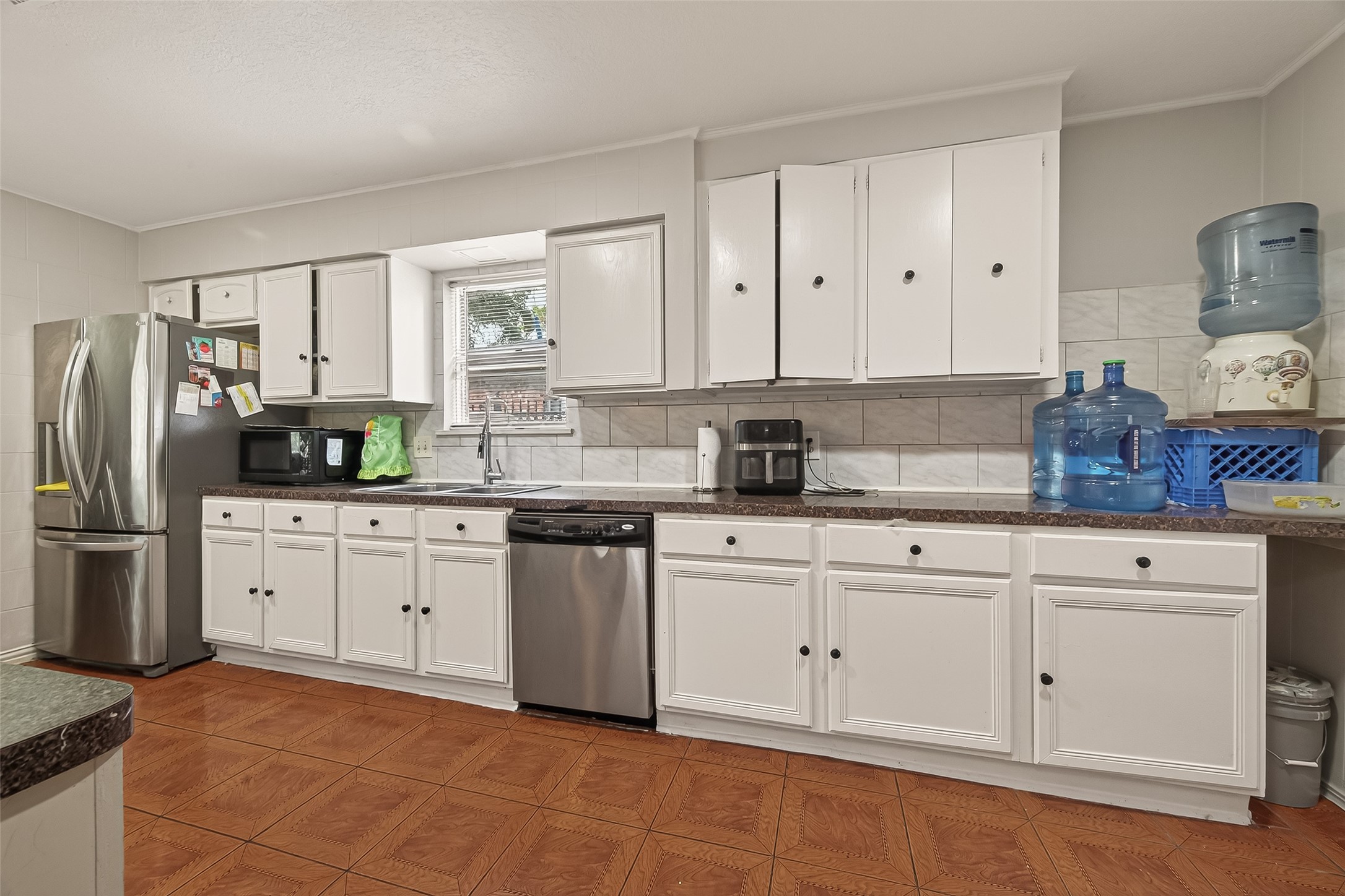 9030 Troulon Drive Houston, TX 77036 - Photo 9 of 34 Bright and functional kitchen featuring white cabinetry, modern stainless steel appliances, and ample counter space for meal preparation.
