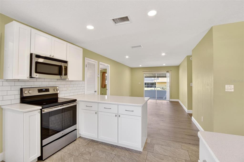2340 Merrily Circle South Seffner, FL 33584 - Photo 34 of 52 a large kitchen with kitchen island granite countertop a stove top oven a sink a counter space and cabinets