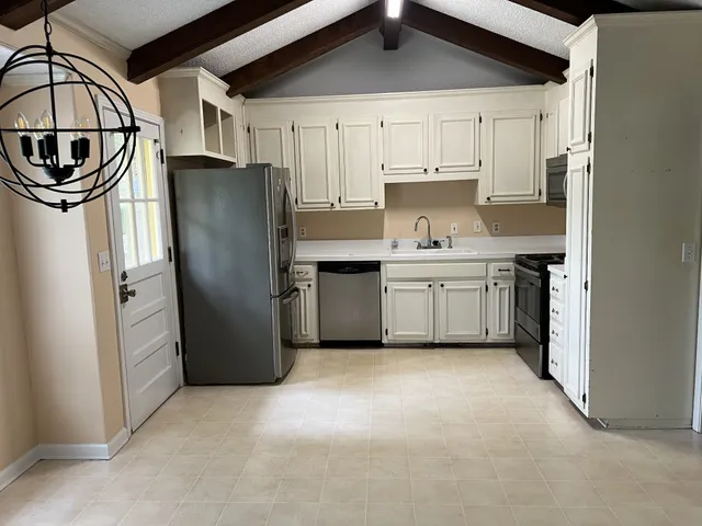 a kitchen with stainless steel appliances granite countertop a refrigerator a stove and a sink