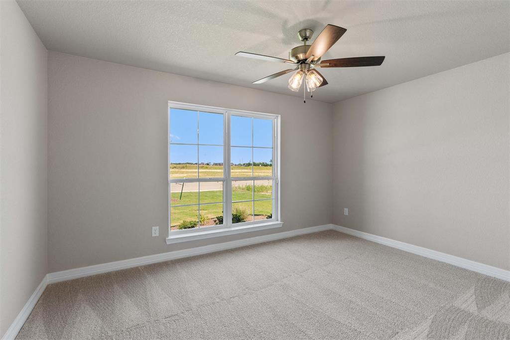 1341 Promised Land Road Hewitt, TX 76643 - Photo 16 of 29 Neutral-toned interior featuring a ceiling fan with integrated lighting, a large window, light gray carpeting, white baseboards, and painted walls
