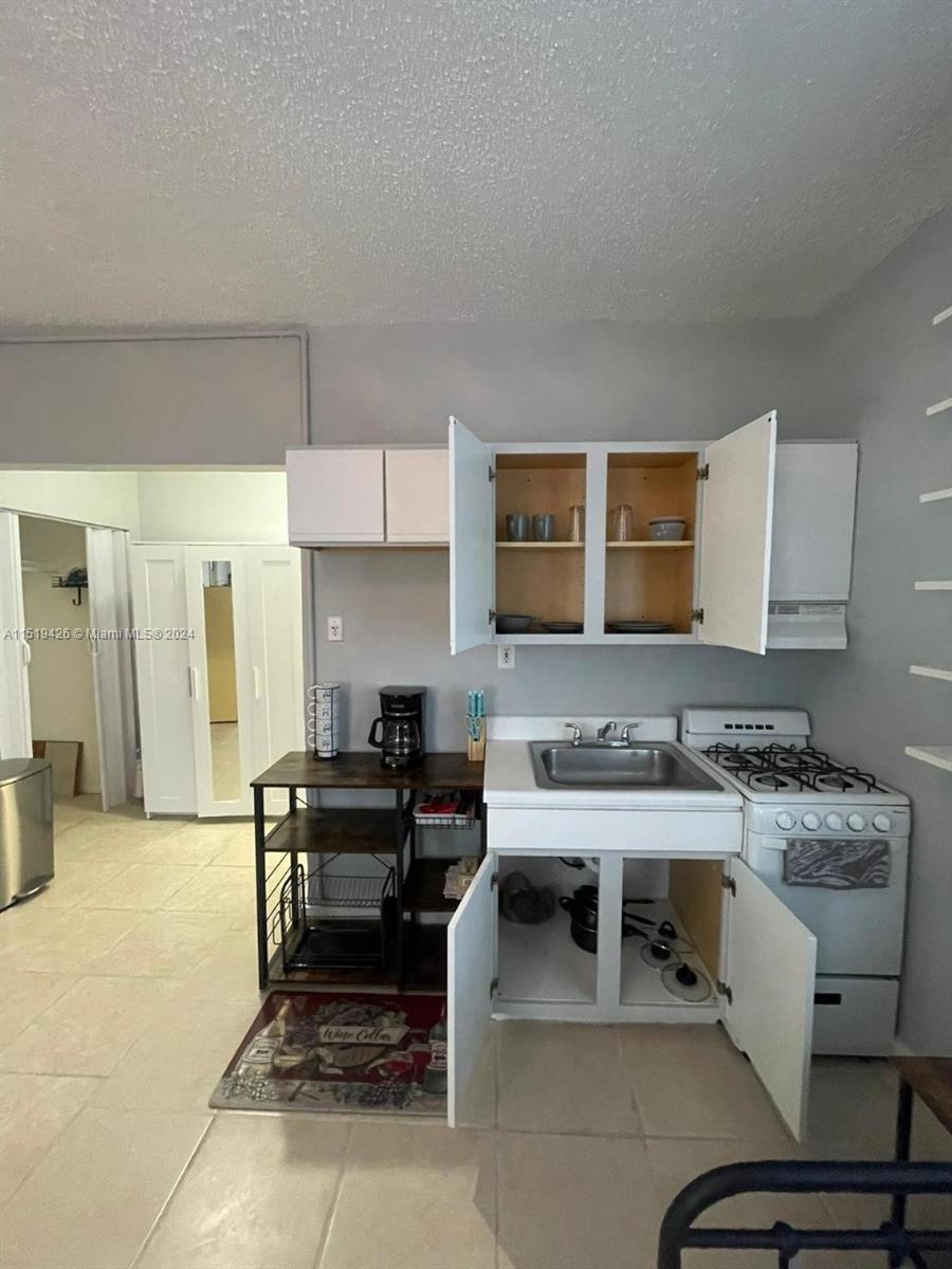 Mid Beach Miami Beach, FL 33140 - Photo 24 of 25 a kitchen with a stove a refrigerator and a counter top space