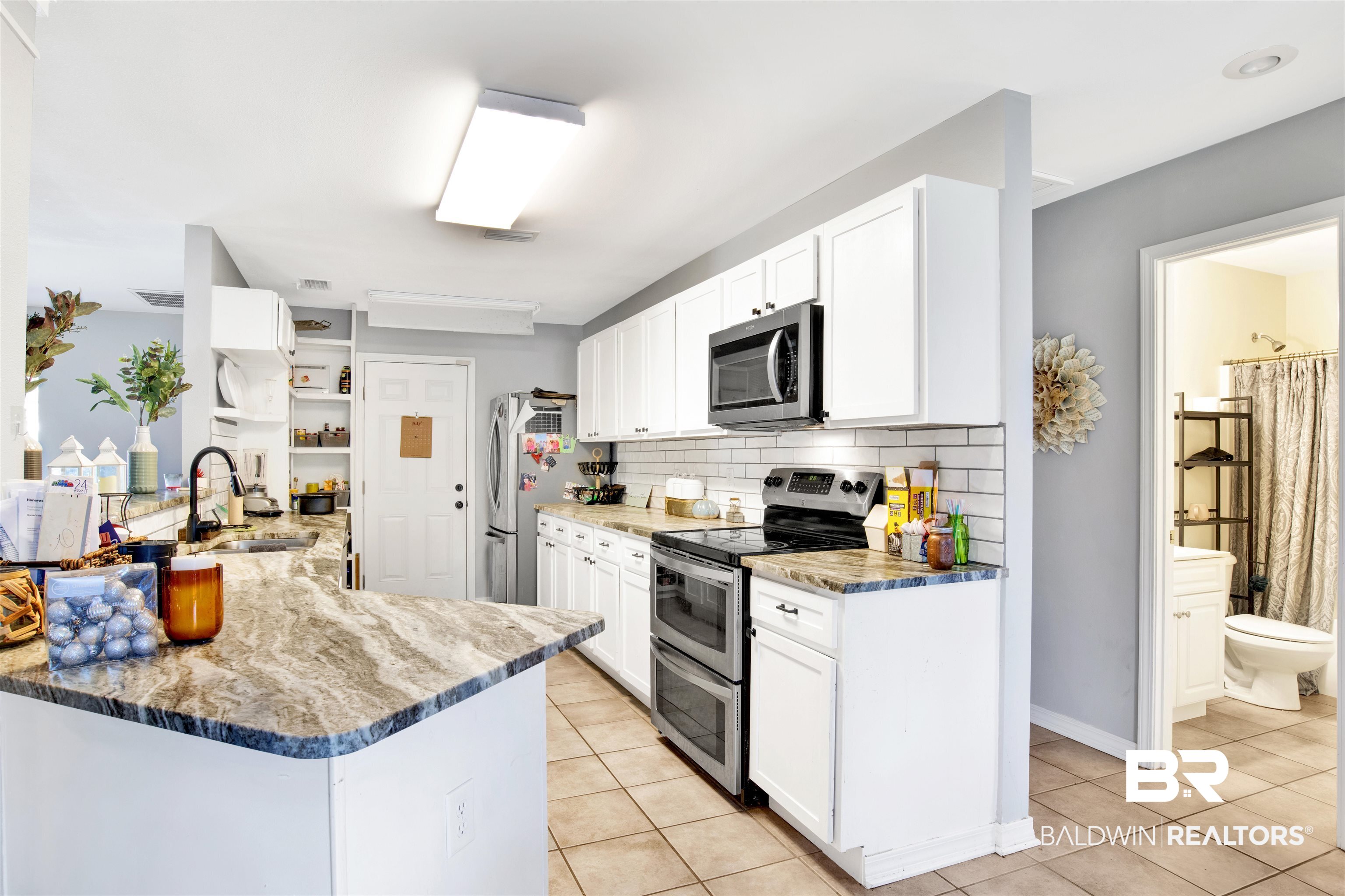 24384 Sailfish Lane Orange Beach, AL 36561 - Photo 6 of 23 Kitchen with sink, white cabinets, kitchen peninsula, and stainless steel appliances