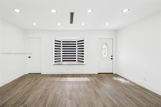 an empty room with wooden floor and window