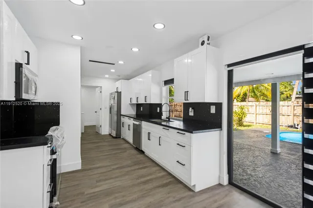 a kitchen with stainless steel appliances a stove top oven a sink a counter top space and cabinets